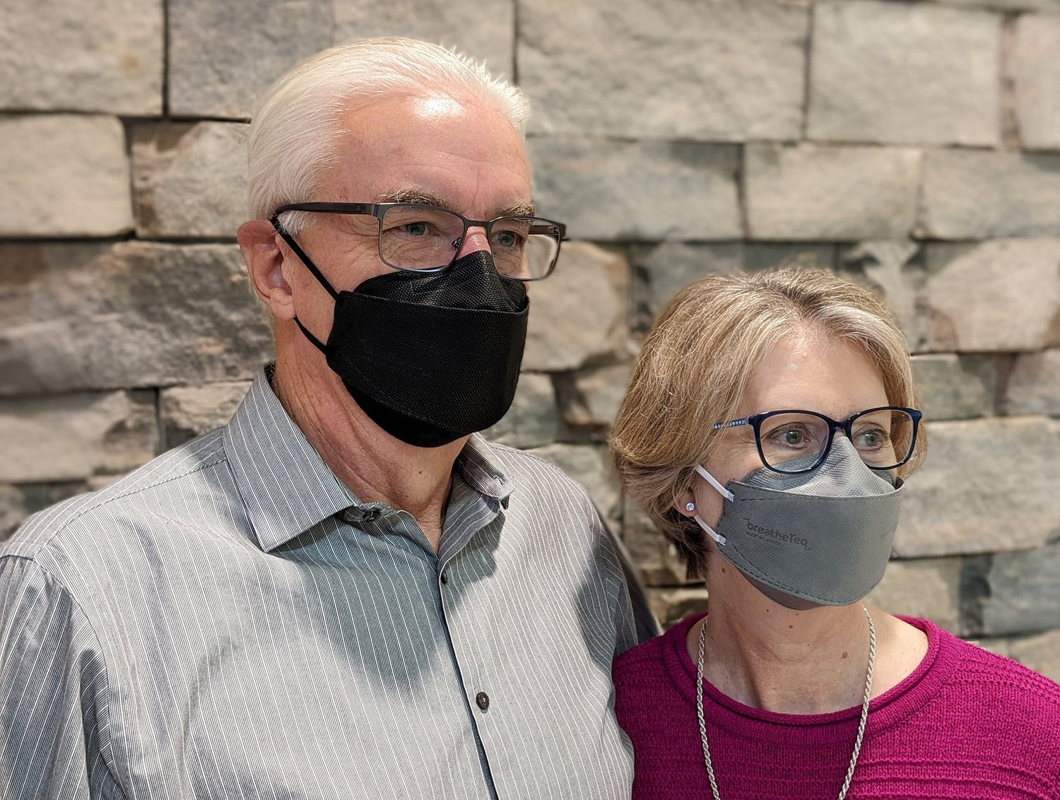 Man wearing large black KN95 and woman wearing medium grey KN95 breatheteq face mask with earloops Made in Canada